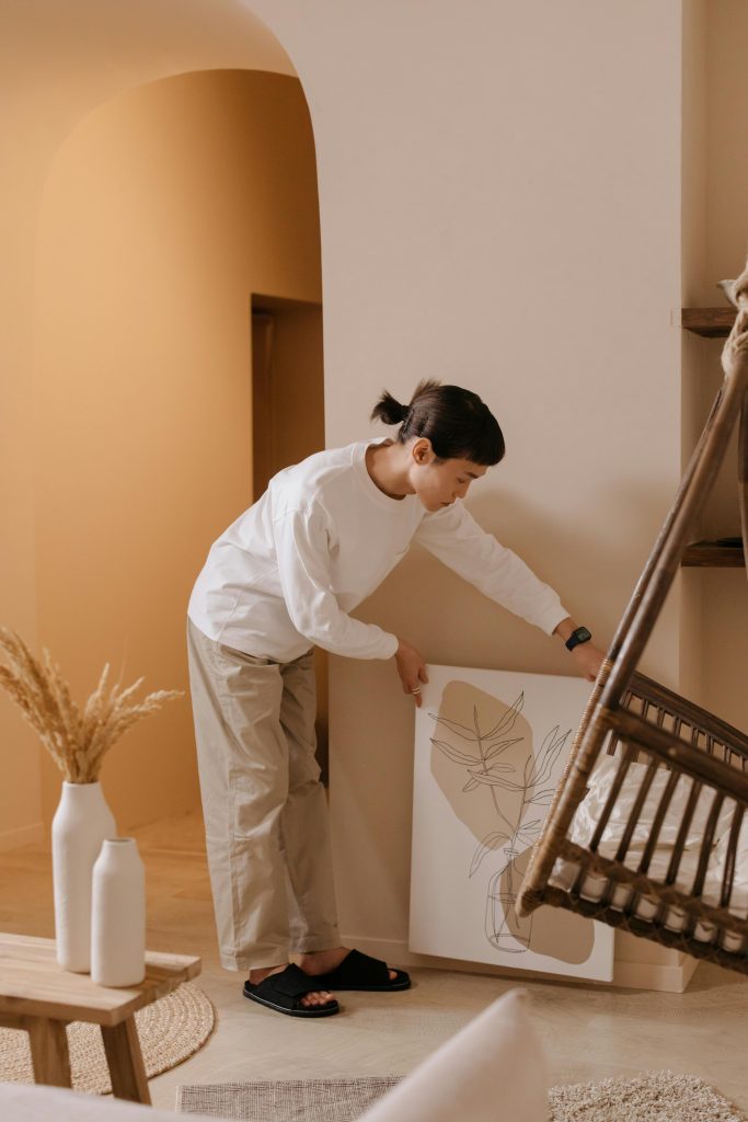 Adult arranging art in a stylish, modern living room with natural decor.
